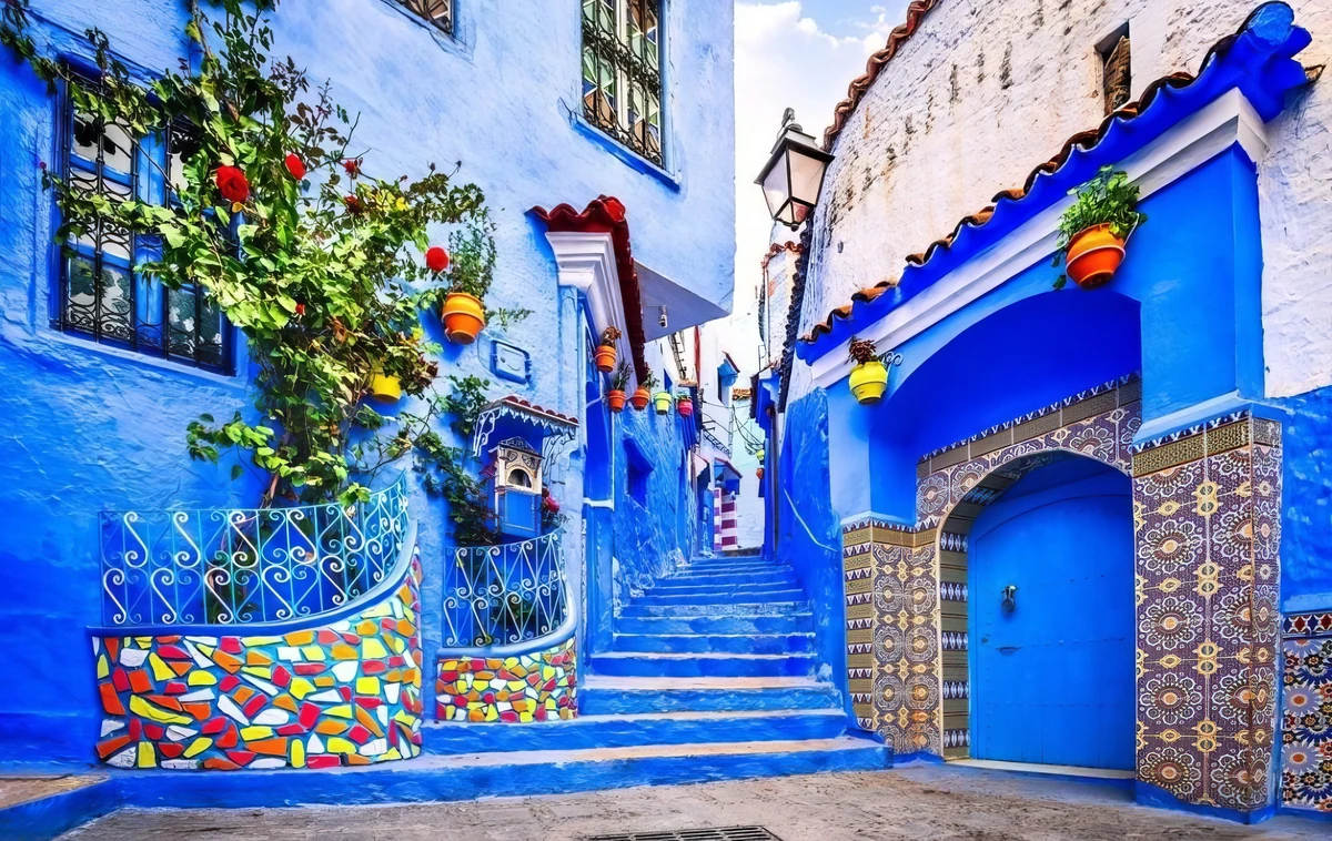 Blue painted Moroccan alley with tiled doorway and flower pots